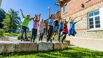 Kinder springen mit ausgestreckten Armen von Gartensteinen herunter