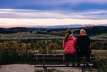 Zwei Personen sitzen auf einer Bank und blicken in die Landschaft