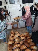 Kinder schieben Brotlaibe in den Ofen