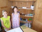 Zwei Kinder stehen im Schulladen aus Holz und verkaufen Hefte
