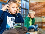 Zwei Jungen hören mit Kopfhörer gespannt zu 