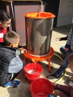 Kinder pressen Saft einer einer Apfelsaftpresse
