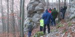 Menschen stehen vor einem großen Fels im Wald